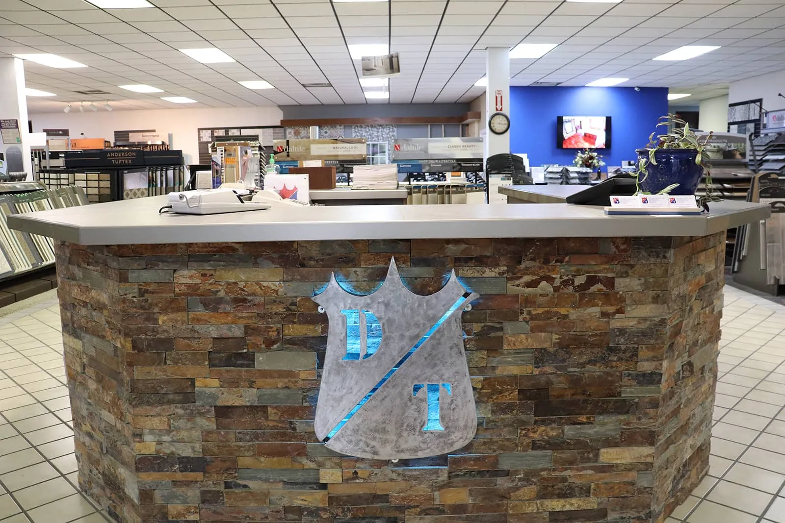 Stone front counter with metal logo inside a tile showroom.