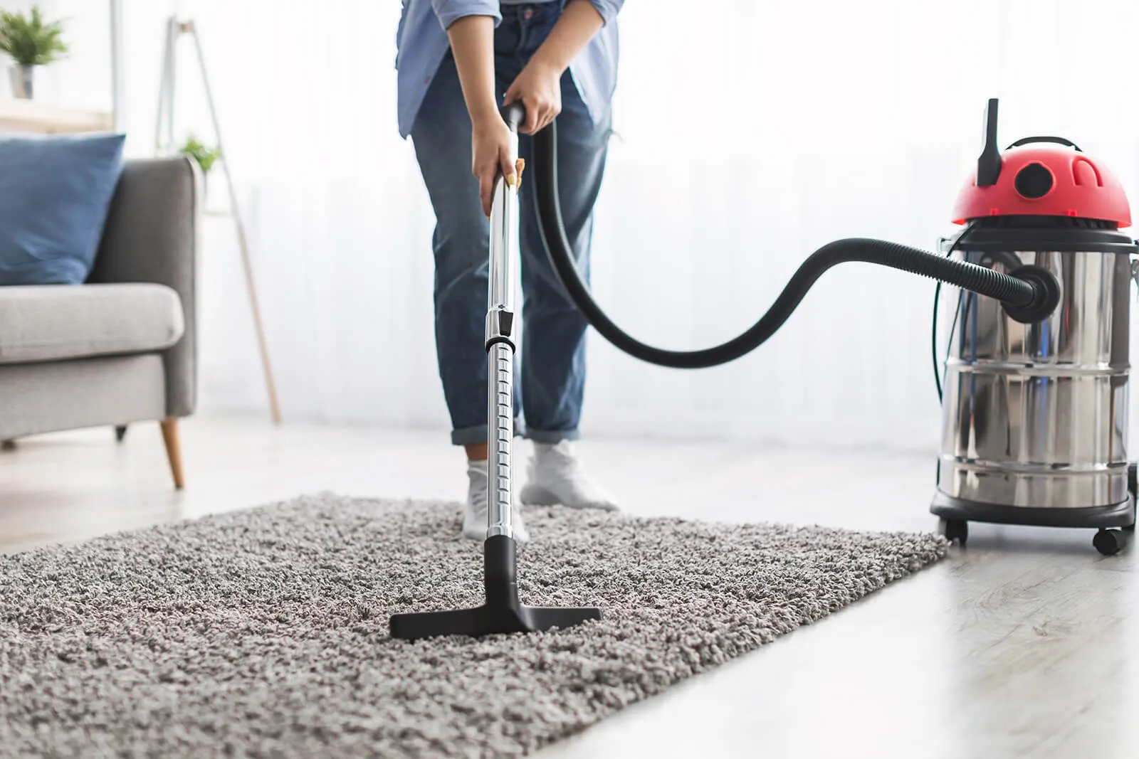 Person vacuuming a grey area rug