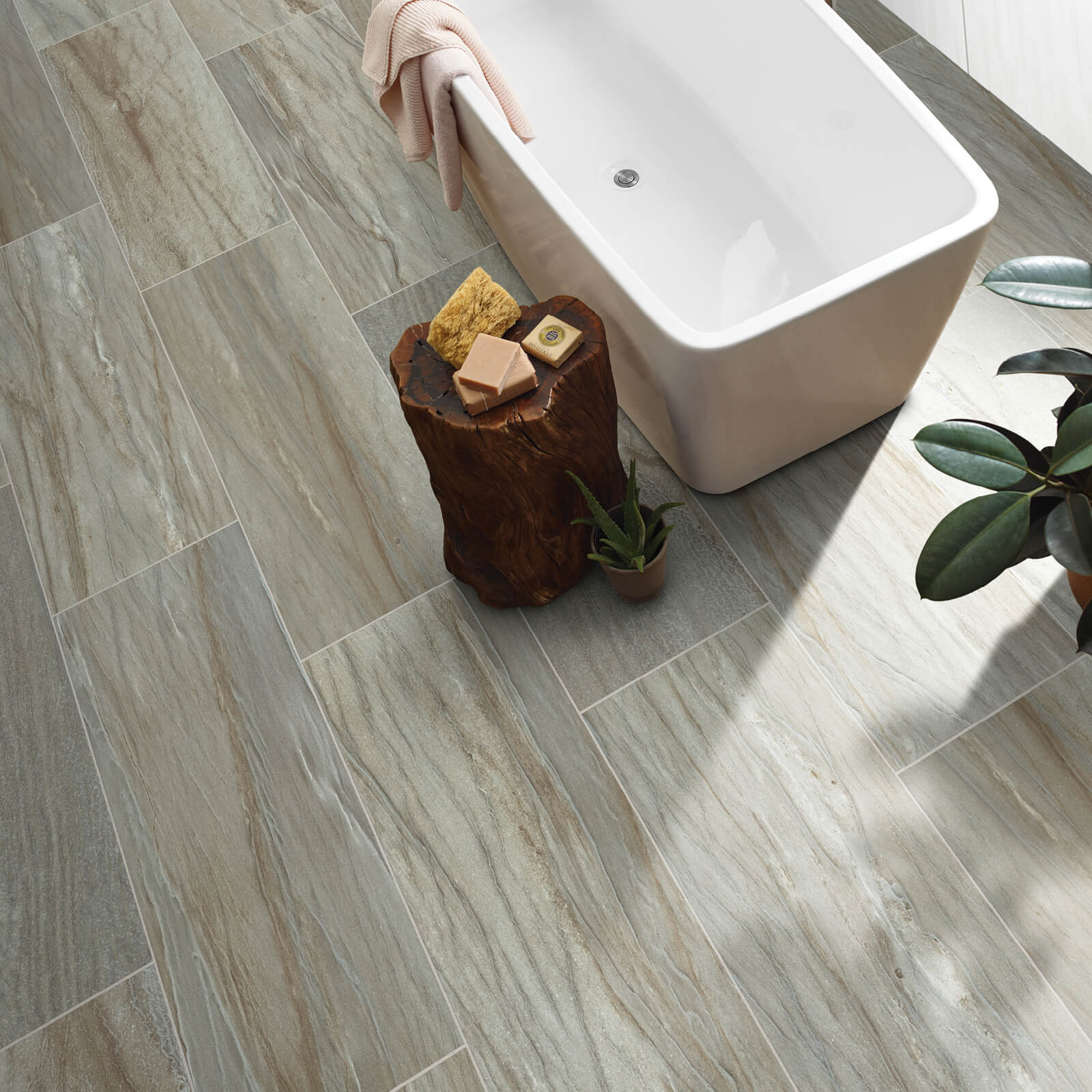 Stone-look tile bathroom floor next to a modern freestanding bathtub.