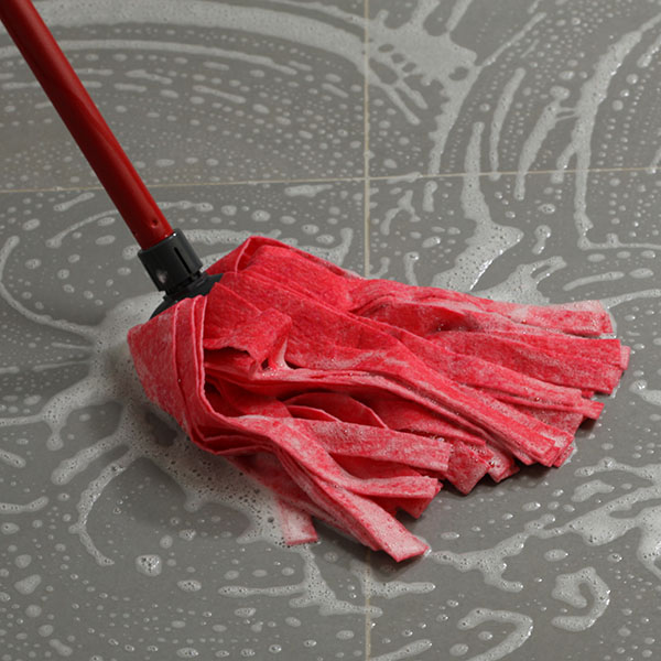 Red mop cleaning a soapy tile floor.