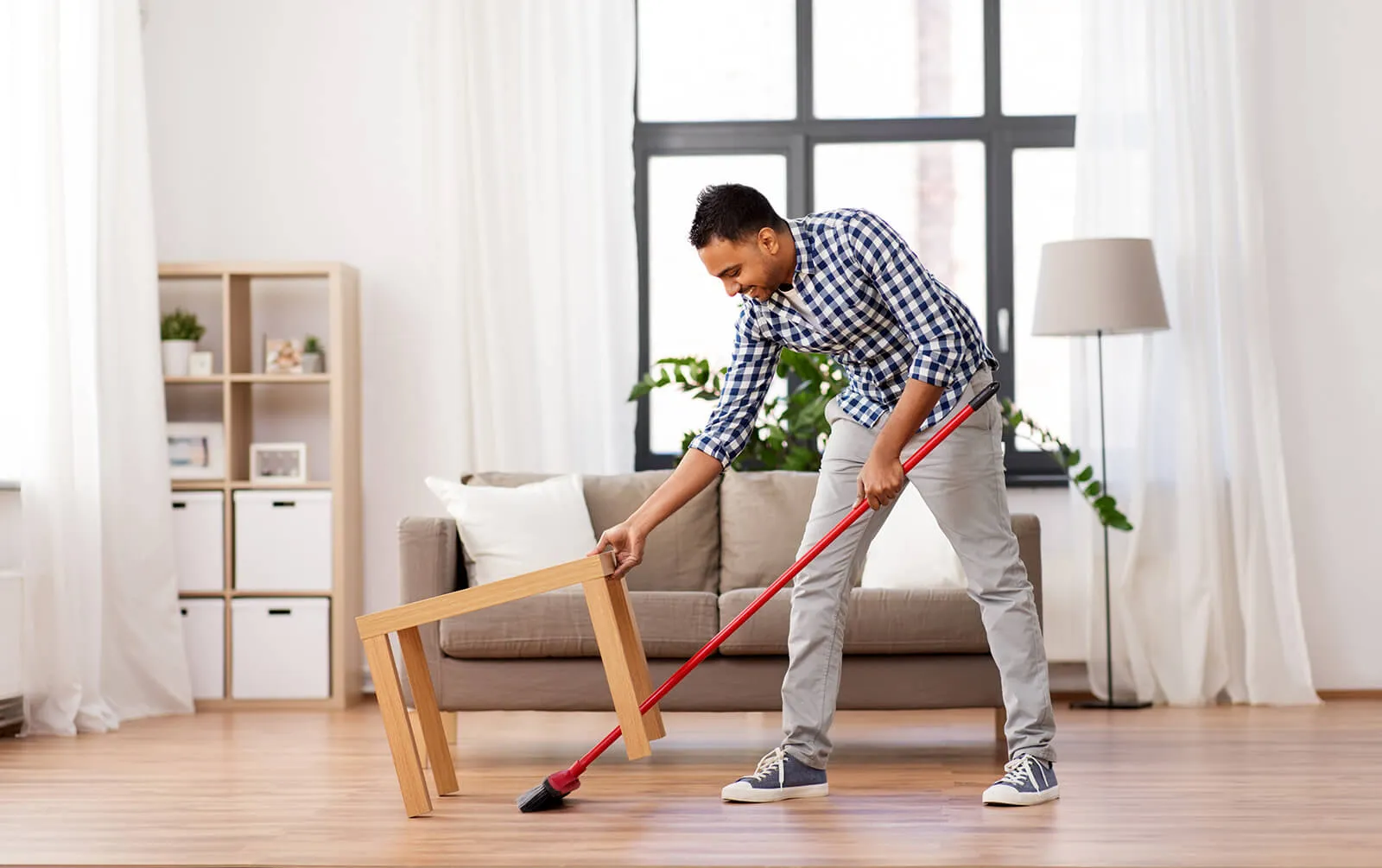 Man sweeping a wood floor with a broom.