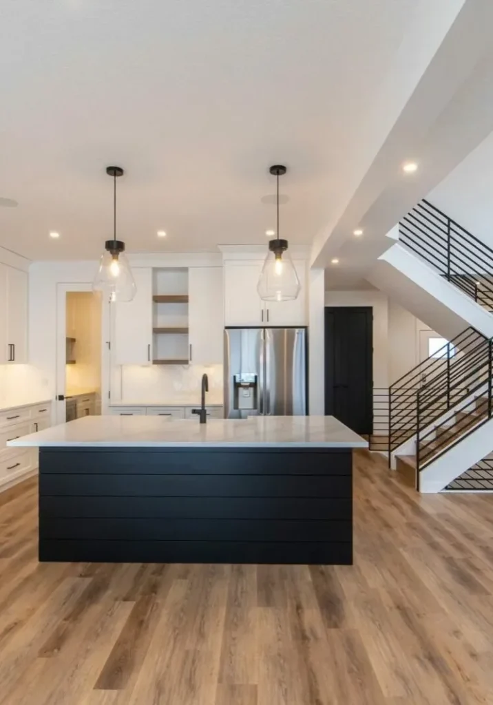 Modern kitchen with a black island and laminate wood flooring.