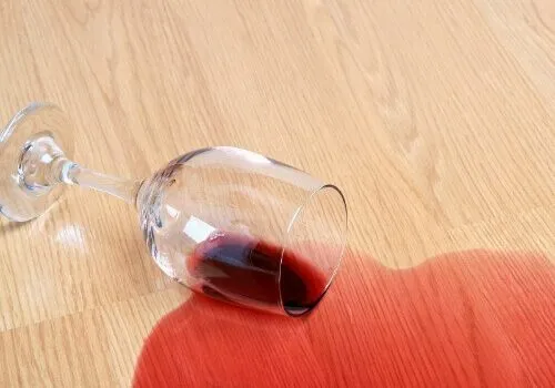 Spilled glass of red wine on a light wood laminate floor.