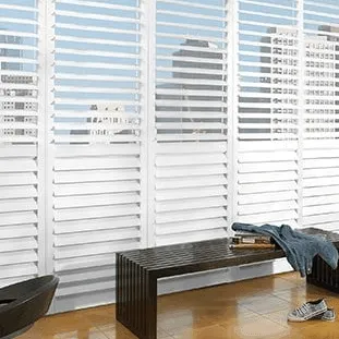 White interior shutters covering full-length windows behind a bench.